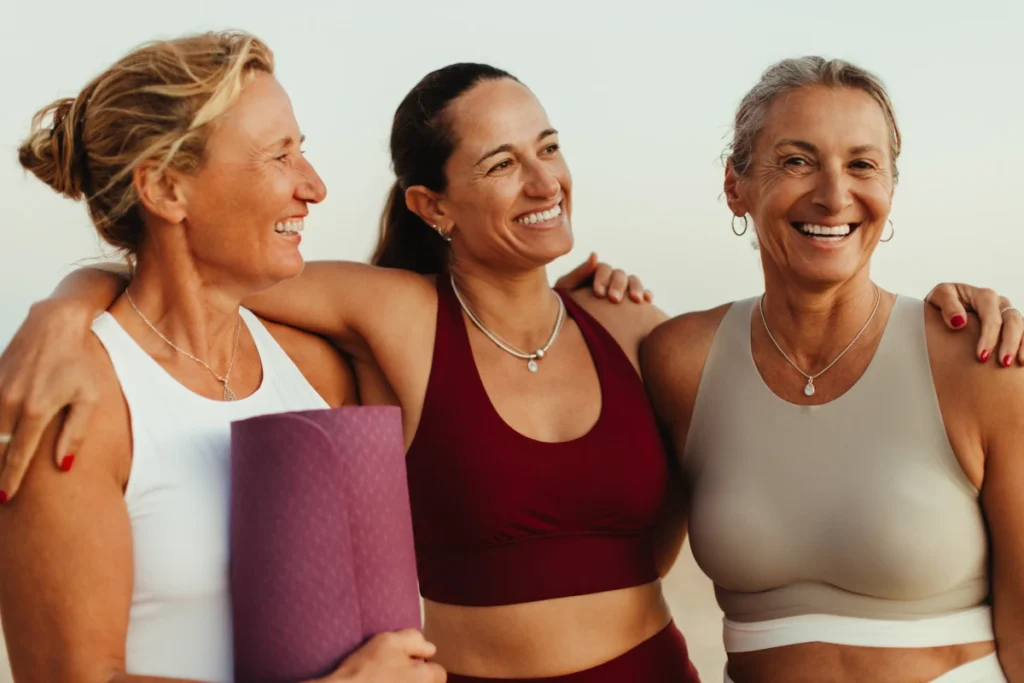 Frauen in Yogakleidung Arm in Arm am Strand
