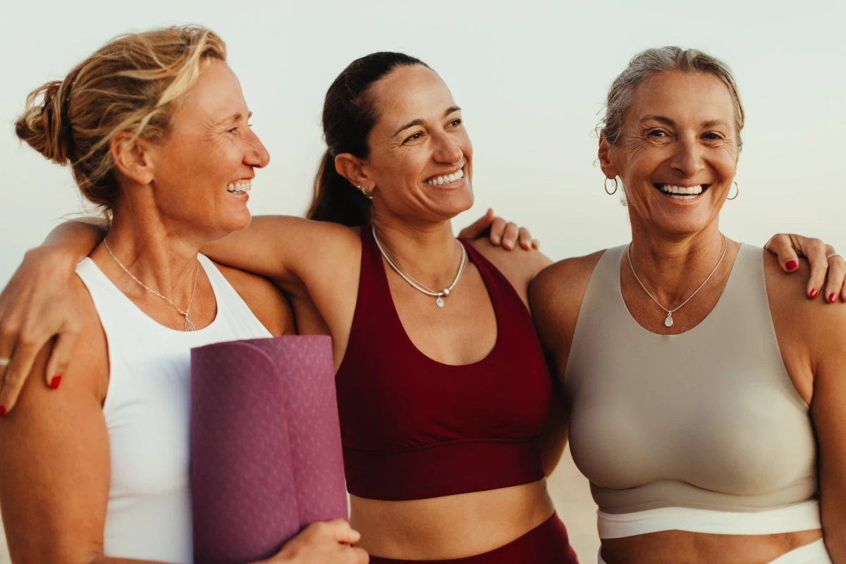 Frauen in Yogakleidung Arm in Arm am Strand