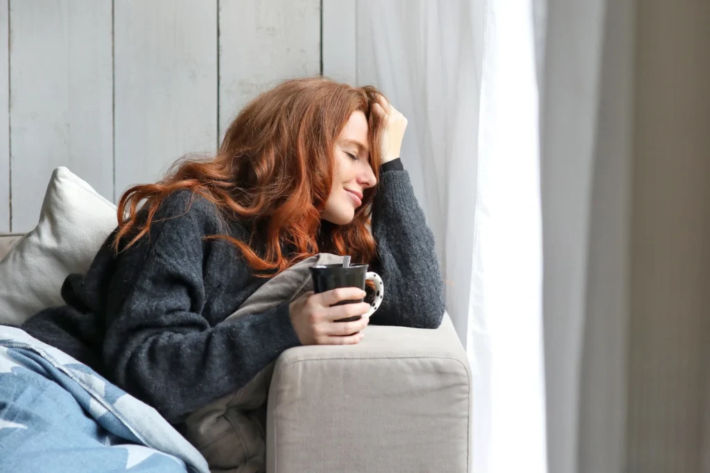 Junge Frau mit Kaffeetasse am Sofa