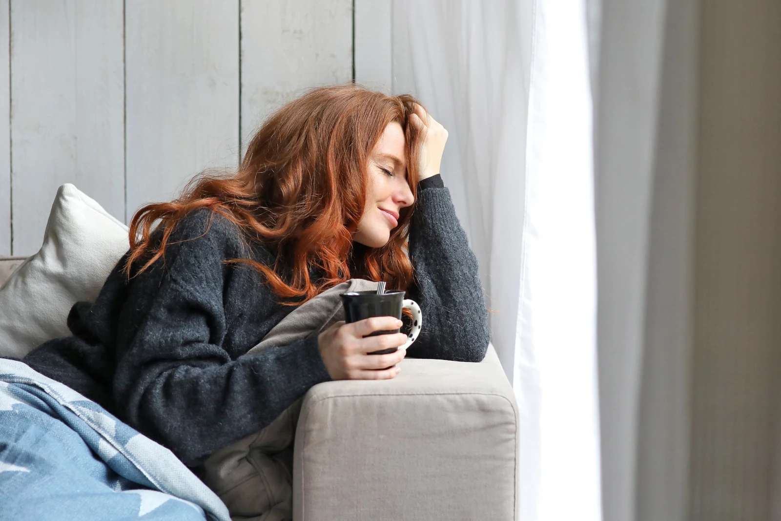 Junge Frau mit Kaffeetasse am Sofa